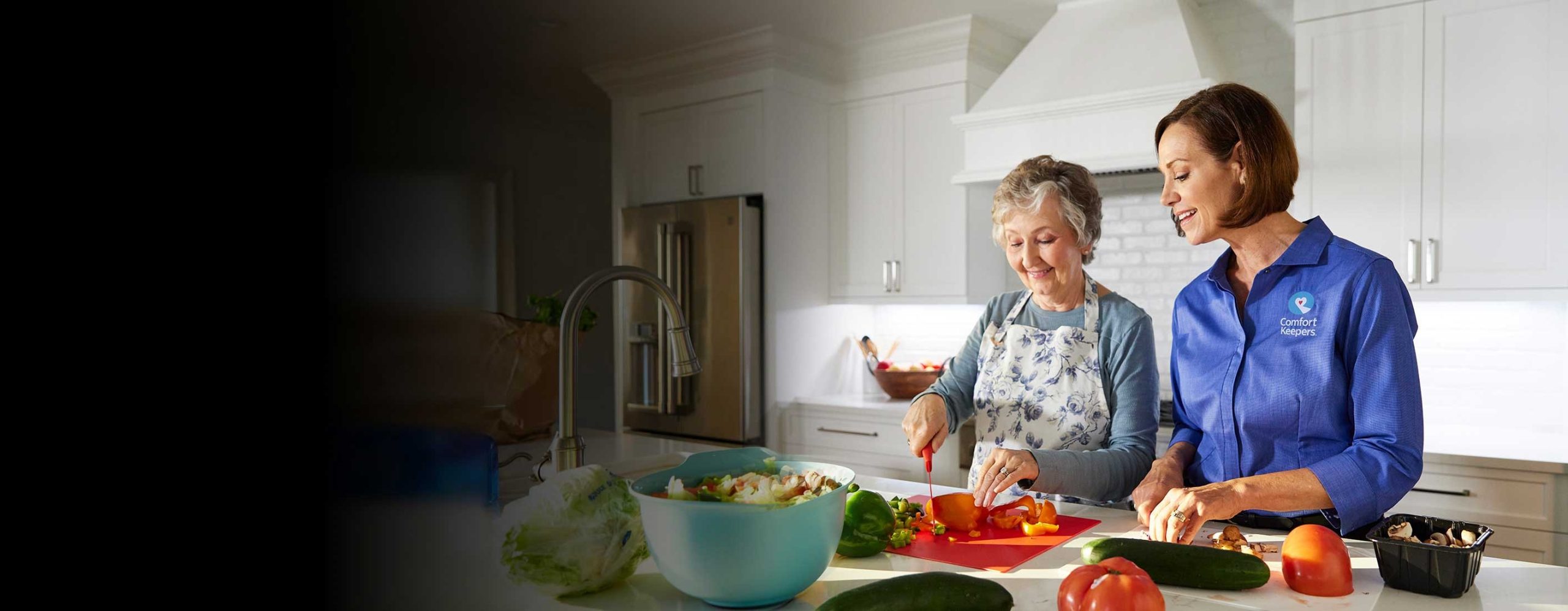 cuidadora a cozer com idosa numa cozinha