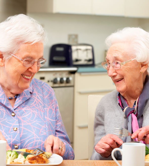Mulheres idosa a conversar e ri numa cozinha
